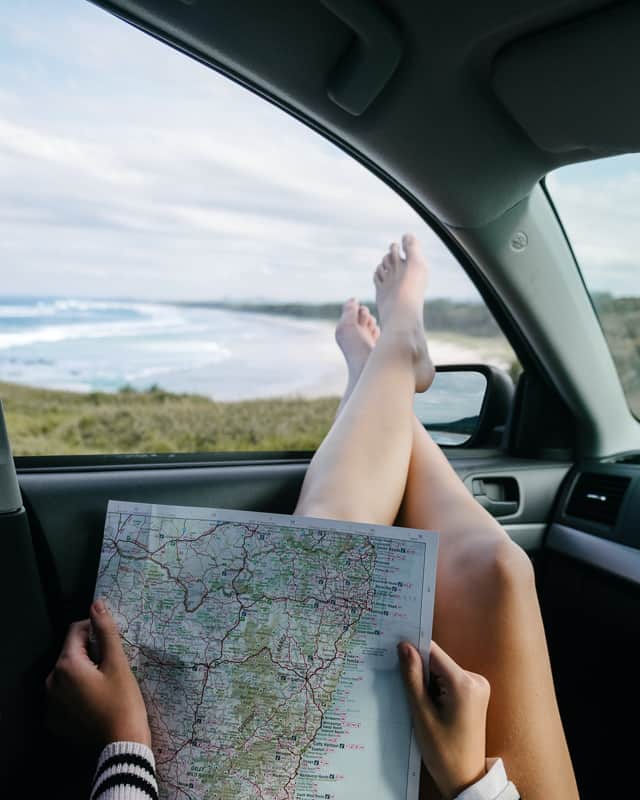 woman with road trip map sitting in a car