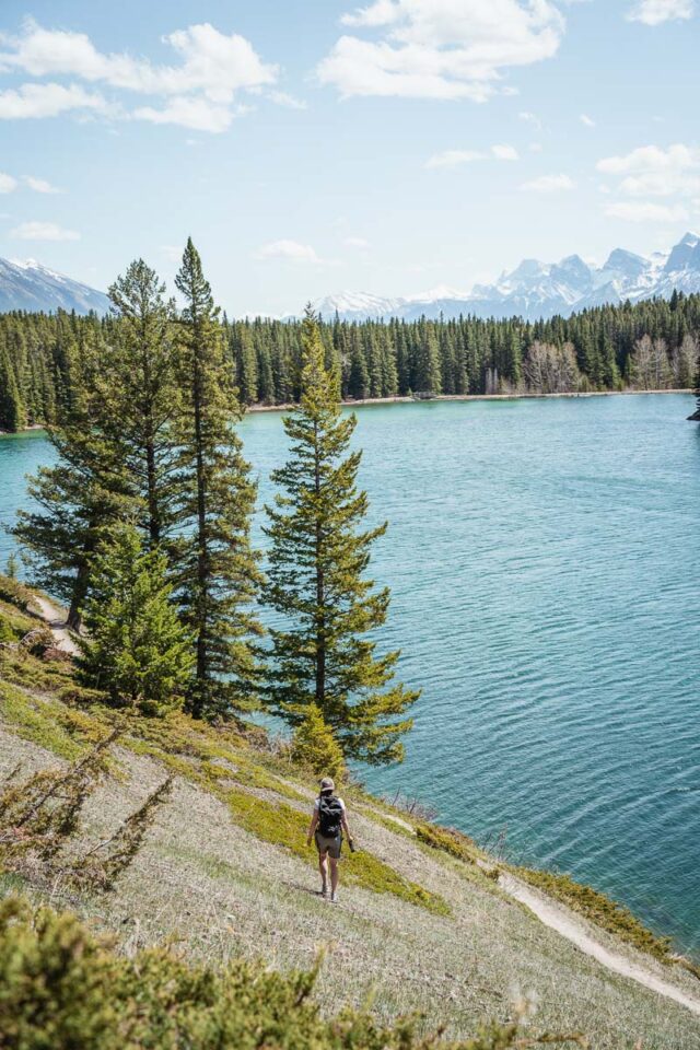 woman walking on mountain trail by the lake, best hikes in banff for beginners